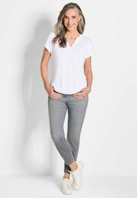 Maglietta bianca a V, jeans slim-fit grigi e sneakers bianche. Design semplice, tessuto leggero e colori neutri. Nessun motivo o accento.