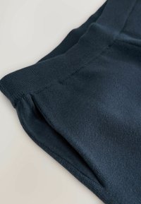 Navy blue sweatshirt fabric with a soft, textured finish. Features a ribbed waistband and stitched detailing near the hem.
