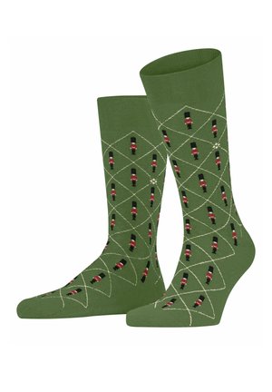 Chaussettes vertes avec des motifs de garde rouges et noirs, présentant un motif en losange souligné de blanc, fabriquées dans un matériau doux et extensible.