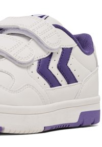 Białe sportowe buty z purpurowymi akcentami. Posiadają gładką syntetyczną cholewkę, rzepy oraz teksturowaną gumową podeszwę. Dwa purpurowe detale w kształcie chevronu.