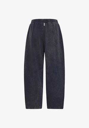 Volné tmavě šedé tepláky s elastickým páskem a malou přední cedulkou, vystavené na bílém pozadí.