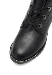 Černá kožená kotníková bota se zaoblenou špičkou, kovovými očky a odpovídajícími tkaničkami. Na chodidle má kontrastní prošívání.