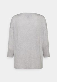 Haut gris clair à manches longues avec une coupe décontractée. Texture douce, encolure ronde et manches trois-quarts. Design simple sans ornements.