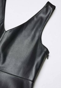 Schwarzes, ärmelloses Kleid aus Kunstleder mit V-Ausschnitt und seitlichem Reißverschluss vor einem weißen Hintergrund.