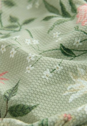Green textured fabric featuring a floral pattern with pink and white flowers, leaves, and a soft, woven design.