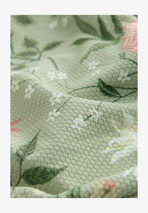Green textured fabric featuring a floral pattern with pink and white flowers, leaves, and a soft, woven design.