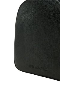 Zaino in pelle nera con texture, forma arrotondata, logo "LOVE MOSCHINO" in rilievo sul fondo e dettagli di cucitura in contrasto.