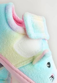 Chaussons doux de couleur pastel avec une texture moelleuse, un design de chat et une bande Velcro. Les couleurs incluent des accents en bleu clair, rose et jaune.