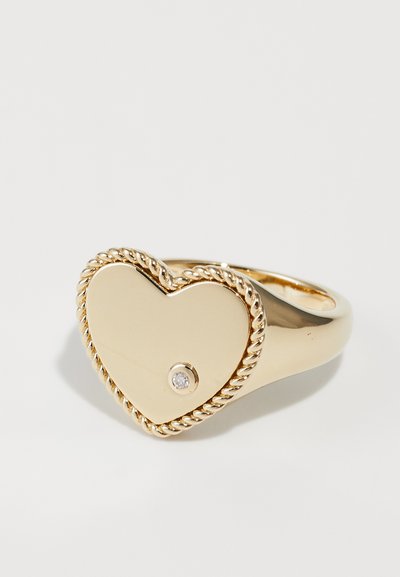 Zelts sirds formā veidots gredzens ar savītas virves rakstu gar malu un mazu dimanta akcentu. Gluda, spīdīga virsma.