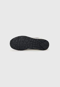 Black rubber outsole features textured grip patterns, designed for traction. The sole curves upward at the heel for stability.