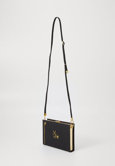 Sac bandoulière rectangulaire noir avec une fermeture éclair dorée, accent logo et sangle réglable en tissu. Texture lisse, design minimaliste.