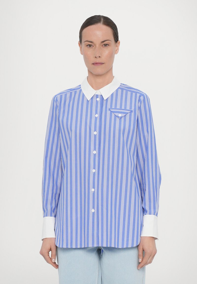 Light blue shirt with white stripes, white collar, long sleeves, and front pocket. Fabric features a smooth texture with button closure.
