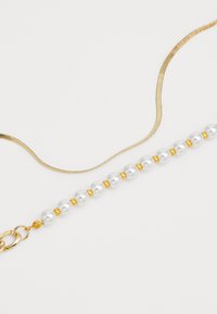 Gold and silver chain necklace featuring white pearls with gold accents. Smooth texture with a lobster clasp closure.