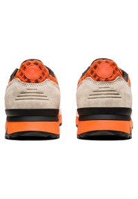 Chaussures de sport en daim et mesh gris et orange avec un arrière texturé, présentant un accent rond et une semelle superposée avec une bande de roulement noire.