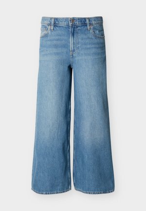 Jean en denim bleu clair à jambes larges avec bouton frontal, fermeture éclair, passants pour ceinture et poches, présenté sur un fond uni.