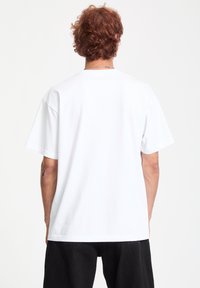 Hvid bomulds t-shirt med korte ærmer, rund hals og afslappet pasform. Har en glat tekstur og minimalistisk design.