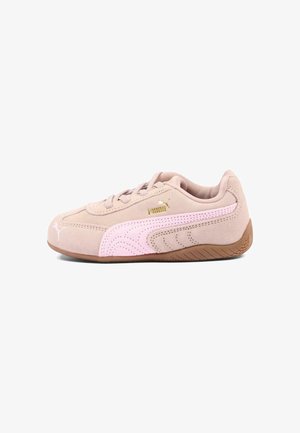 Lichtbruine suède Puma sneaker met een lichtroze streep, een bruine zool en een gouden Puma-logo, zijaanzicht op een witte achtergrond.