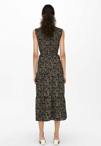 Maxiklänning i lättviktsmaterial med svart- och beige leopardmönster, med korta ärmar och flerfaldig fåll. Bärs med vita klackskor med öppen häl.