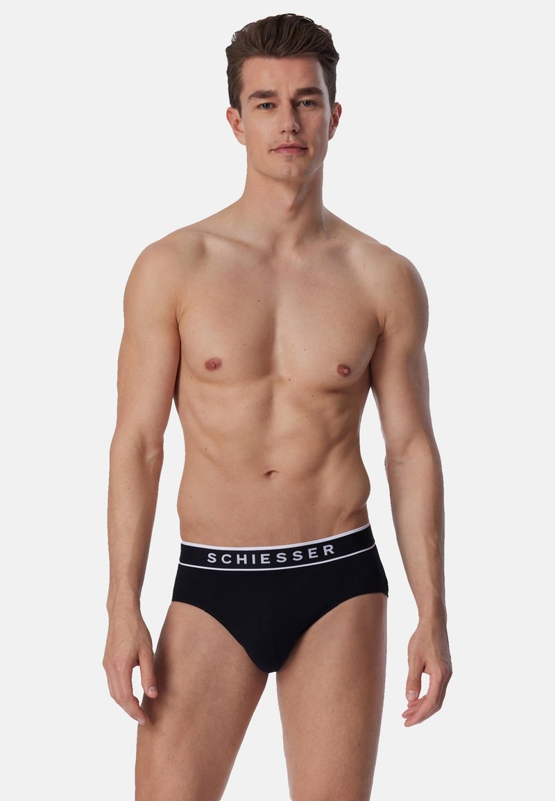 Culotte noire en coton doux avec une ceinture blanche arborant le nom de la marque "SCHIESSER" en lettres épaisses. Coupe ajustée.