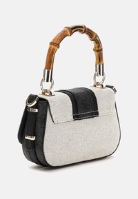 Sac à main texturé noir et blanc avec une poignée en bambou, quincaillerie en argent et une forme structurée présentant une fermeture à rabat et des éléments décoratifs.