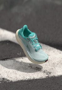 Light turquoise running shoe with a breathable mesh upper, textured surface, and cream-colored sole, featuring minimalist design and lacing.
