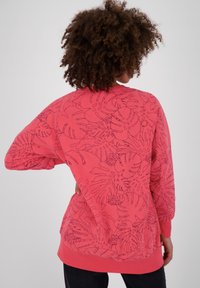 Felpa rossa con un motivo floreale, dotata di maniche lunghe, polsini a coste e una vestibilità rilassata. Materiale in cotone liscio con disegni contornati.