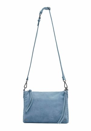 Sac bandoulière en daim bleu clair avec bandoulière réglable, fermeture éclair et pompons décoratifs sur fond blanc.
