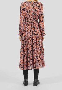 Vestido negro de manga larga con un estampado paisley en naranja y rosa. Presenta una cintura ajustada y una falda de volantes, que se combina con botas negras hasta el tobillo.