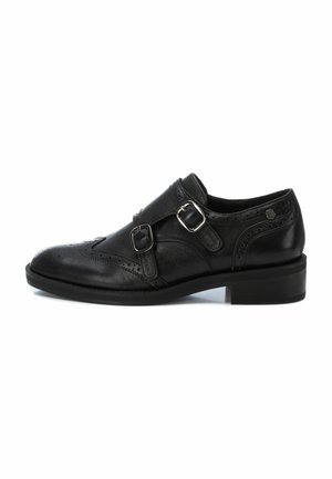 Zapato de vestir de cuero negro con dos correas de hebilla plateadas. Presenta detalles de brogue, punta redonda, tacón de 2.5 cm y textura suave.