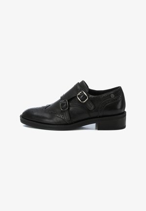 Zapato de vestir de cuero negro con dos correas de hebilla plateadas. Presenta detalles de brogue, punta redonda, tacón de 2.5 cm y textura suave.