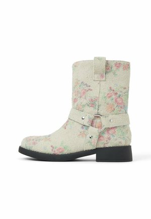 Bottes en tissu texturé vert pâle avec un motif floral rose et bleu, une bride latérale avec un anneau métallique, et un talon noir robuste.