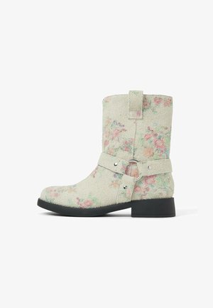 Botas con una tela texturizada de color verde pálido con un patrón floral en rosa y azul, una correa lateral con un anillo metálico y un taco negro resistente.