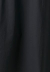 Tissu noir avec de subtils plis verticaux et une texture douce, affiché uniformément sans motifs ni autres éléments.