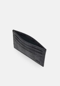 Sorth cardholder lavet af tekstureret materiale. Har flere rum og et mønstret design, med en grøn inderside.