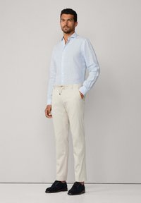 Hellblaue gestreifte Hemdbluse, cremfarbene Hose und marineblaue Wildlederschuhe; Slim Fit; bemerkenswerte Details sind der Kragen und der strukturierte Stoff.