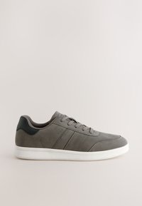 Baskets basses grises avec détail talon noir, lacets sur le devant et semelle en caoutchouc blanche sur fond neutre.
