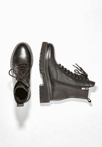 Stivali in pelle nera con punta rotonda, chiusura con lacci, zip laterale, suola chunky e borchie decorative attorno alla caviglia e alla punta.