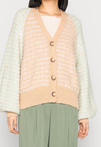 Dziergany kardigan w pastelowym brzoskwiniowym i miętkowym kolorze, z dekoltem w serek, oversize'owymi rękawami, zapięciem na guziki i teksturowanym wzorem.