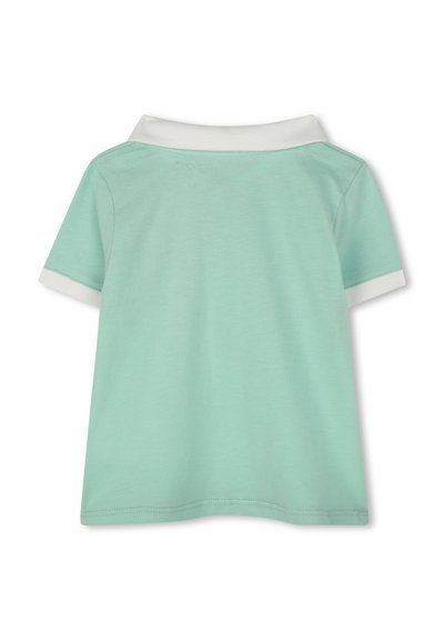 Polo vert menthe avec un col blanc replié, des manches courtes, une texture lisse et un ourlet piqué. Pas de motifs visibles ni de détails en matériel.