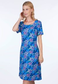 Blumenkleid mit blauer Grundfarbe und rosa-lila Blumenmustern, kurzen Ärmeln und einem quadratischen Ausschnitt. Glatte Stofftextur.