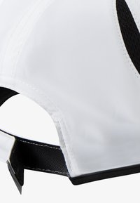 Gorra blanca hecha de tela suave con detalles de malla negra. Cuenta con una visera curva, correa ajustable y detalles de costuras visibles en la superficie.