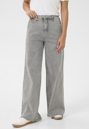 Jeans de pierna ancha en denim gris claro con una cintura alta. Presenta bolsillos delanteros y un acabado limpio, combinados con zapatillas blancas.