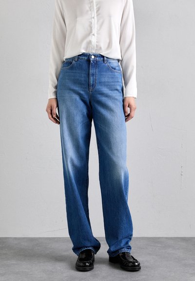 Lysblå højtaljede jeans med lige ben, med slidte detaljer, bæltestropper og klassisk fem-lomme stil. Sættes sammen med en hvid skjorte.