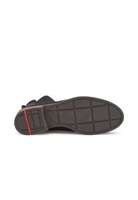 Semelle extérieure en caoutchouc noir avec un motif de grip texturé. Présente une bande d'accent rouge près du talon et a un design supérieur lisse.