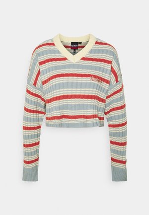 Pull cropped rayé en bleu clair, rouge et crème. Il présente un col en V, une texture côtelée et un logo brodé sur la poitrine gauche.