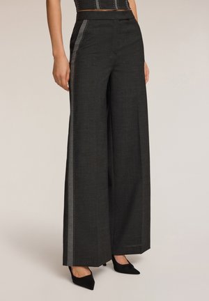 Pantaloni neri a gamba larga realizzati in tessuto testurizzato, con strisce laterali a contrasto e dettagli di cucitura discreti. Vita sagomata per un aspetto strutturato.
