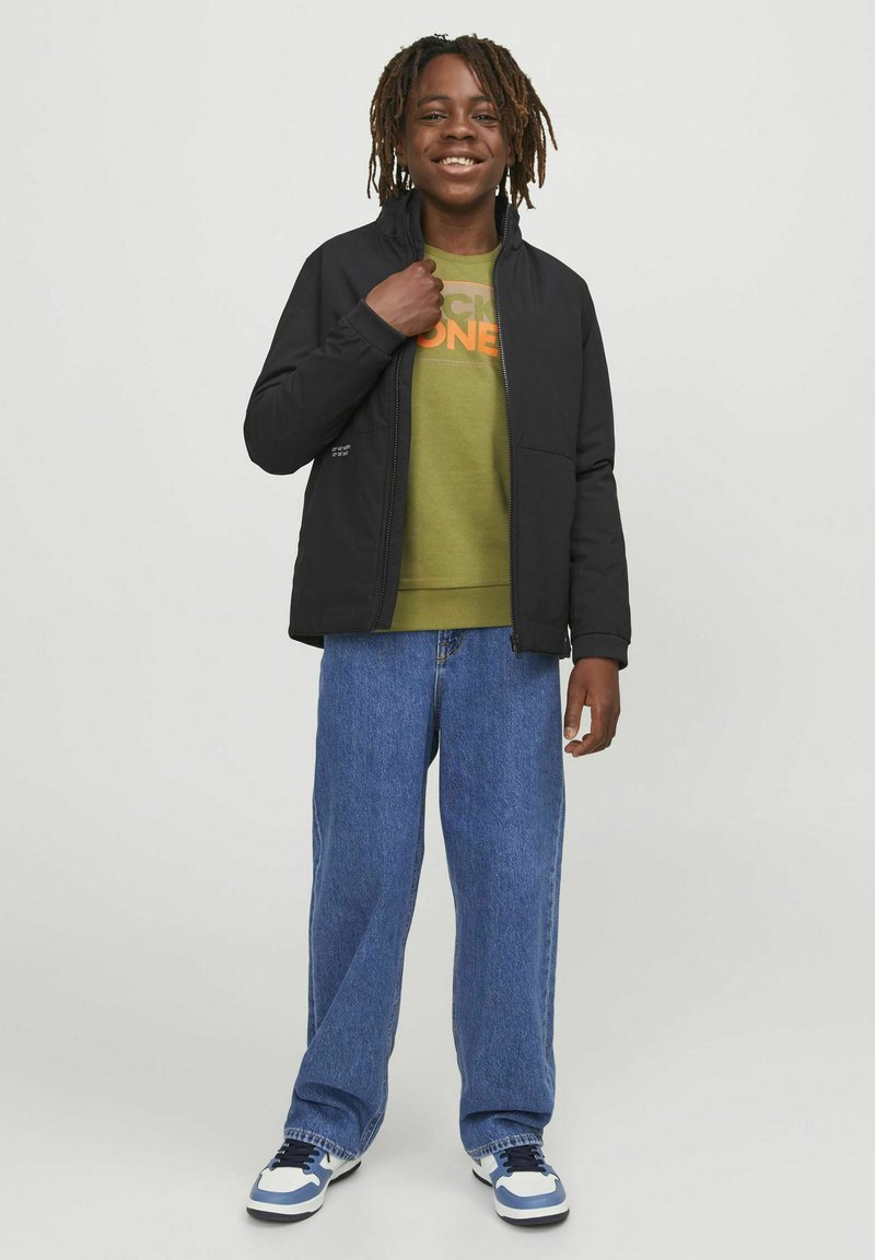 Svart zip-up jacka, grön sweatshirt med orange text, blå denimjeans och svart-vita sneakers. Avslappnad passform med en avslappnad silhuett.