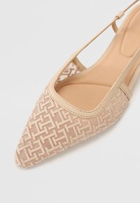 Chaussure beige à bout pointu avec tige texturée tissée et une fine bride, vue de dessus sur un fond clair uni.