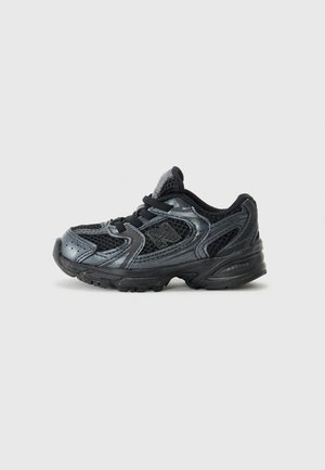 Black athletic shoe with mesh and synthetic materials, rounded toe, thick cushioned sole, and black laces, featuring a shiny texture.