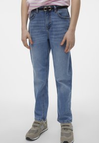 Jeans in denim celeste con una vestibilità a gamba dritta, cuciti con un classico design a cinque tasche, abbinati a una cintura nera e a sneakers grigie.